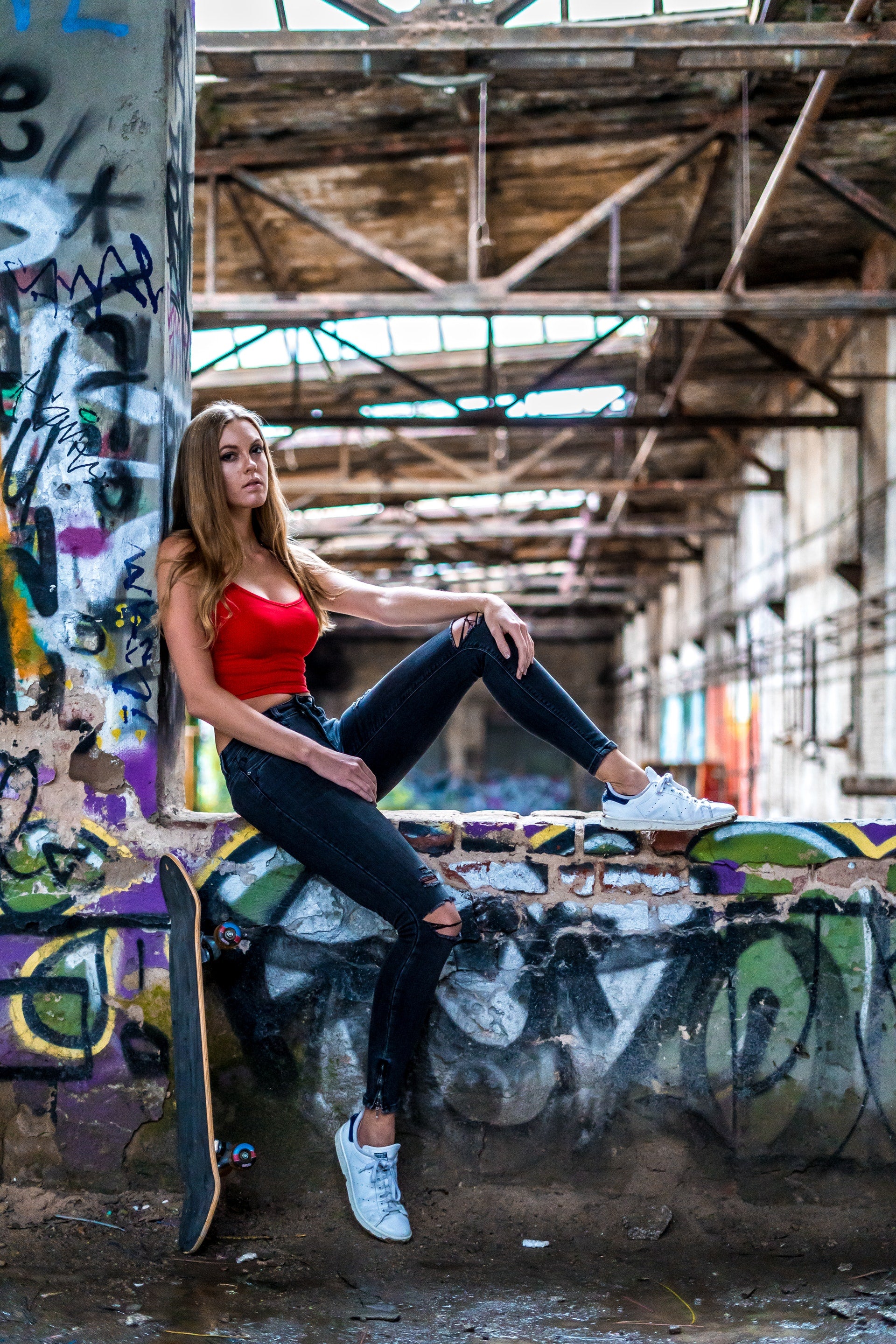 jeune femme posant devant un décor indsutriel style usine abandonnée